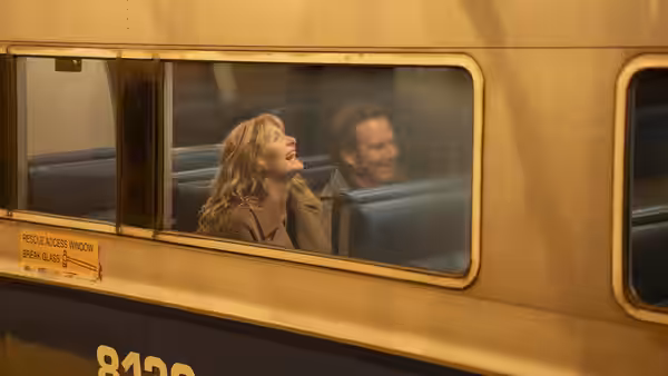 Tess Novak (Laura Dern) laughing beside Alex Novak (Will Arnett) on a train