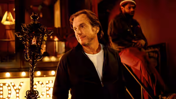 Alex Novak (Will Arnett) standing in a theater lobby looking aside