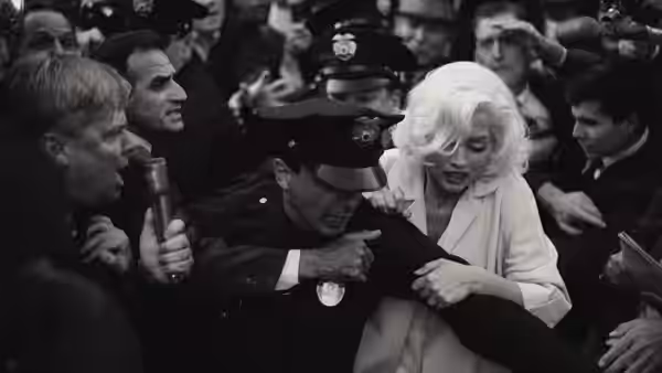 Marilyn Monroe (Ana de Armas) is escorted through a crowd by uniformed police officers