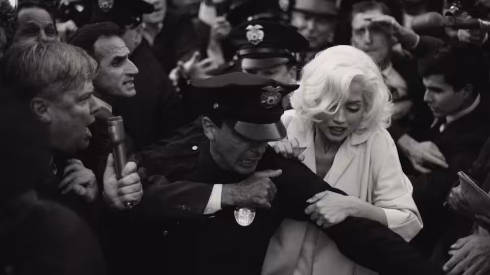 Marilyn Monroe (Ana de Armas) is escorted through a crowd by uniformed police officers