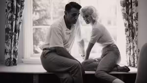 Marilyn Monroe (Ana de Armas) and a man sit together on a windowsill