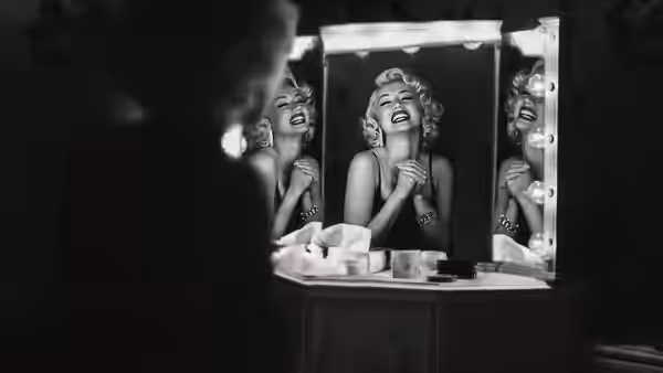 Marilyn Monroe (Ana de Armas) laughs at herself in a lit dressing-room mirror