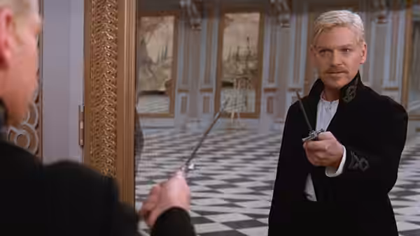 Prince Hamlet (Kenneth Branagh) holding a sword while facing another man