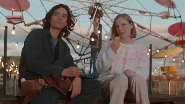 a man and woman sitting together at a carnival at dusk