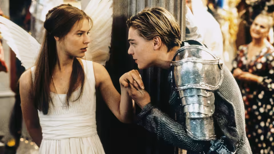 Juliet (Claire Danes) and Romeo (Leonardo DiCaprio) holding hands while gazing closely