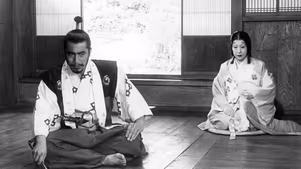 Taketoki Washizu (Toshirō Mifune) sits cross-legged beside Lady Asaji (Isuzu Yamada) indoors