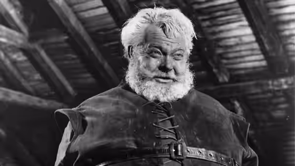 Falstaff (Orson Welles) stands beneath the beams of a timbered hall