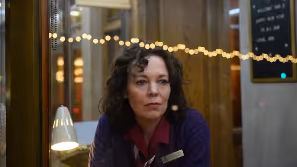 Hilary (Olivia Colman) leans on a counter inside the cinema