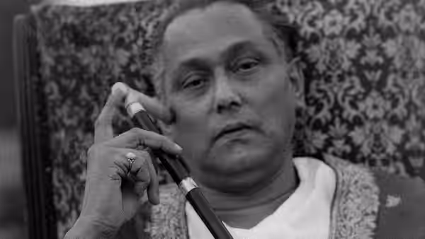 Biswambhar Roy (Chhabi Biswas) holds a pen near his face