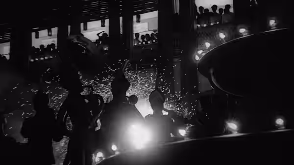 Silhouetted musicians perform on a dim stage before seated spectators