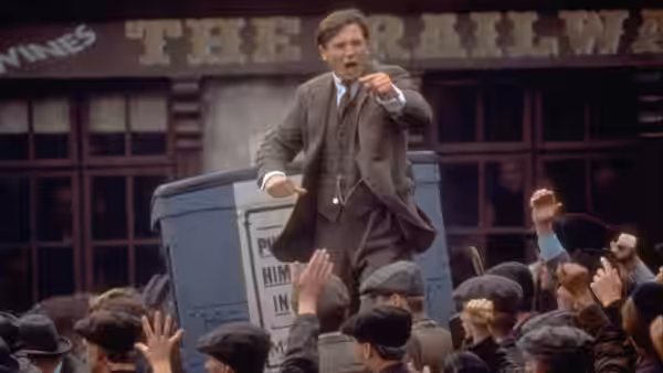 Michael Collins (Liam Neeson) gesturing to a crowd from atop a bin