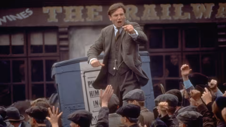 Michael Collins (Liam Neeson) gesturing to a crowd from atop a bin