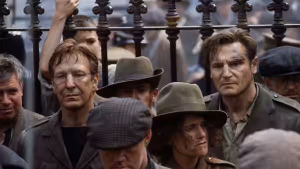 A group of men standing together behind an iron fence, one bloodied