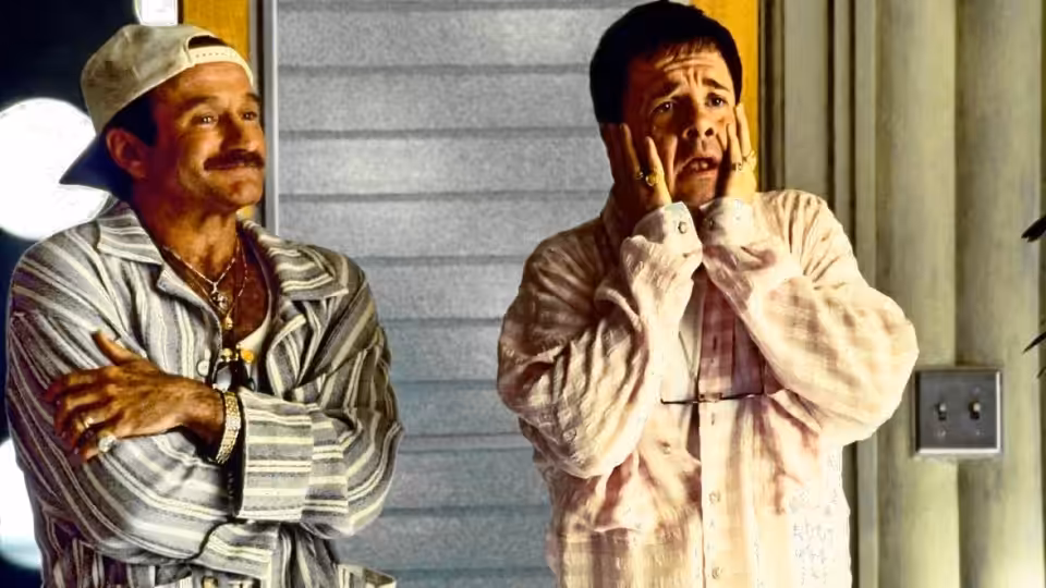Agador (Hank Azaria) with arms crossed beside Armand Goldman (Robin Williams) holding his cheeks