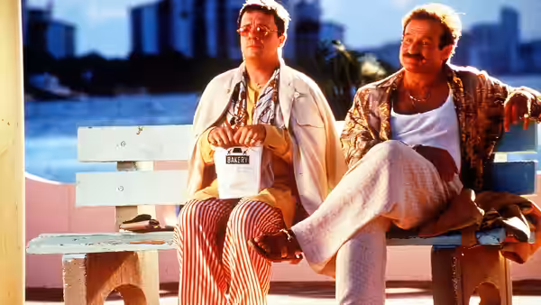 Armand Goldman (Robin Williams) and Val Goldman (Dan Futterman) seated on a waterfront bench