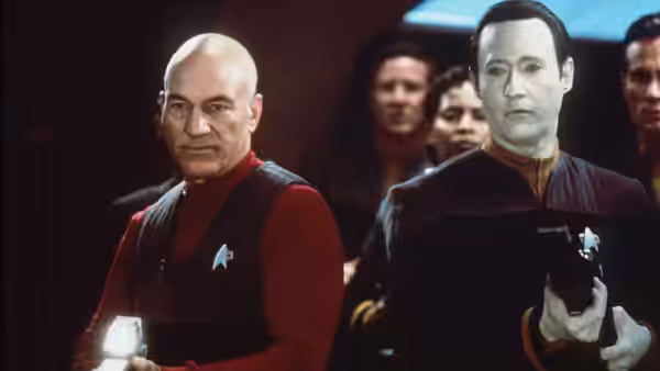 Picard (Patrick Stewart) stands beside Data (Brent Spiner) holding a phaser
