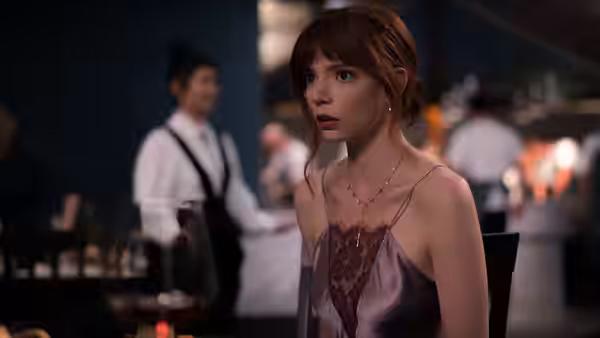Margot (Anya Taylor-Joy) stands in the restaurant as staff work behind her