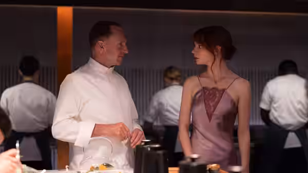 Tyler (Nicholas Hoult) and Margot (Anya Taylor-Joy) talk beside the kitchen counter