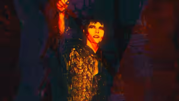 David Bowie (David Bowie) stands in a patterned suit beneath warm stage lighting