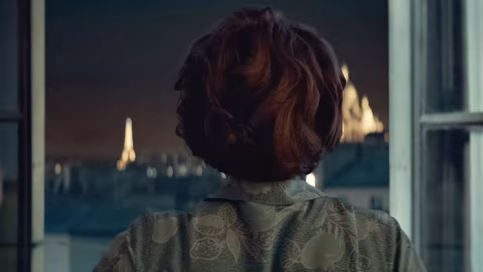 Ada Harris (Lesley Manville) looks out a Paris window toward the Eiffel Tower
