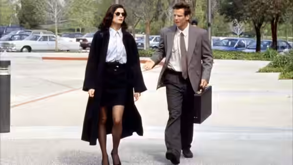 Bridget Gregory (Linda Fiorentino) walks through a parking lot beside a suited man carrying a briefcase