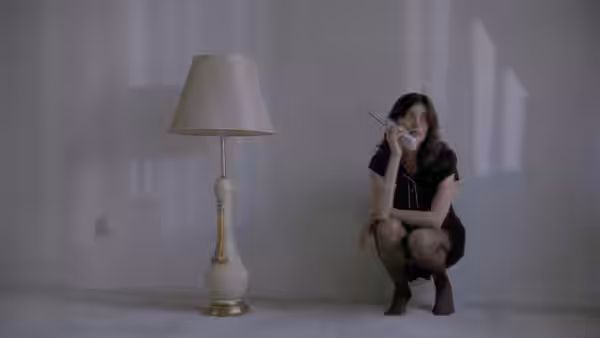 Bridget Gregory (Linda Fiorentino) crouches beside a floor lamp, speaking on a telephone