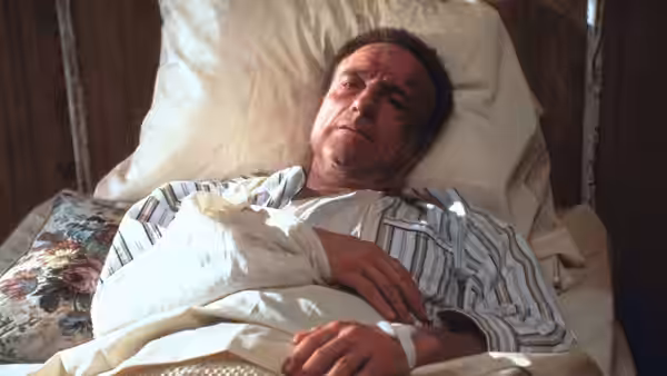 Paul Sheldon (James Caan) resting in bed with arm and leg casts