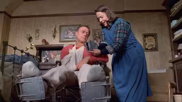 Paul Sheldon (James Caan) in bed with Annie Wilkes (Kathy Bates) beside him