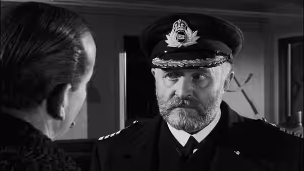 A bearded captain in uniform faces a woman in his cabin