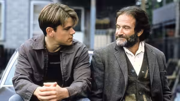 Will Hunting (Matt Damon) and Sean Maguire (Robin Williams) seated outdoors near a building