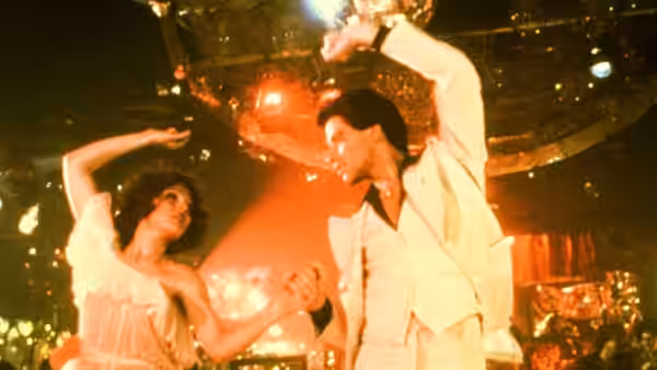 Tony Manero (John Travolta) dancing with a woman under a disco ball