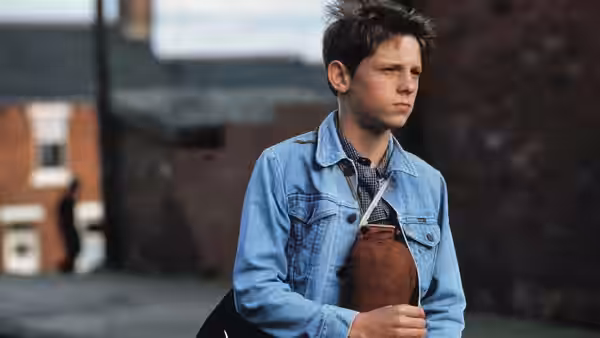 Billy Elliot (Jamie Bell) walking outdoors with a bag over his shoulder