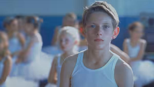 Billy Elliot (Jamie Bell) standing in a ballet class wearing a white vest