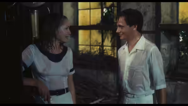 A dark-haired woman and young man talk beside a lit window
