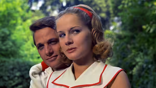 Micòl (Dominique Sanda) stands in the garden with a young man behind her
