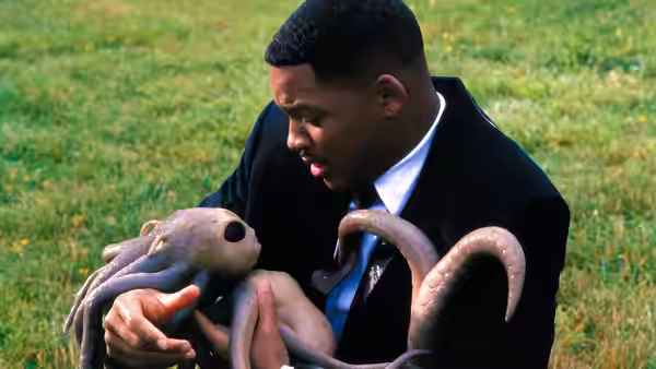 Jay (Will Smith) holding a small tentacled alien on the grass