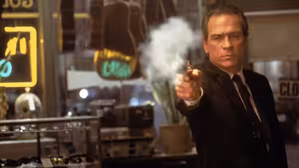 Kay (Tommy Lee Jones) firing a handgun inside a shop at night