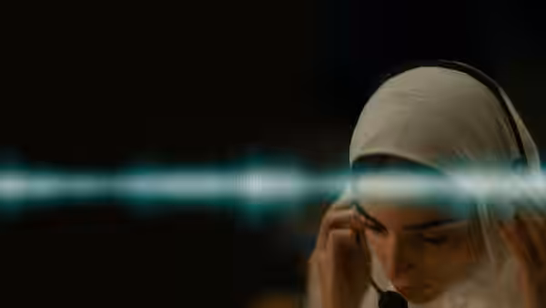 Woman in white hijab and headset listens with eyes closed