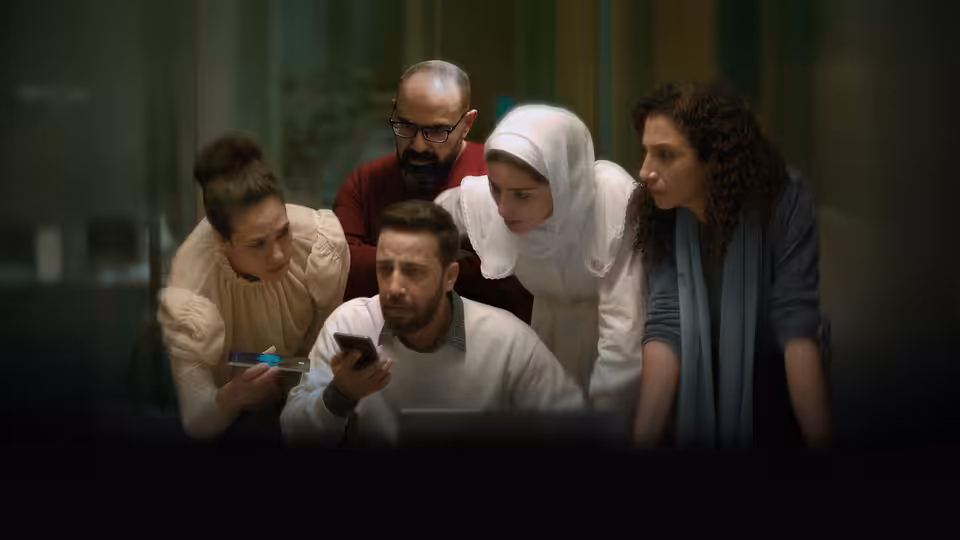 Five colleagues gather closely around a smartphone in an office