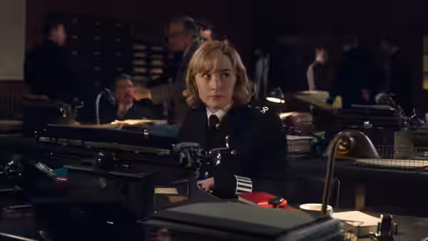 Constable Stalker (Saoirse Ronan) sits at a typewriter in a busy police office