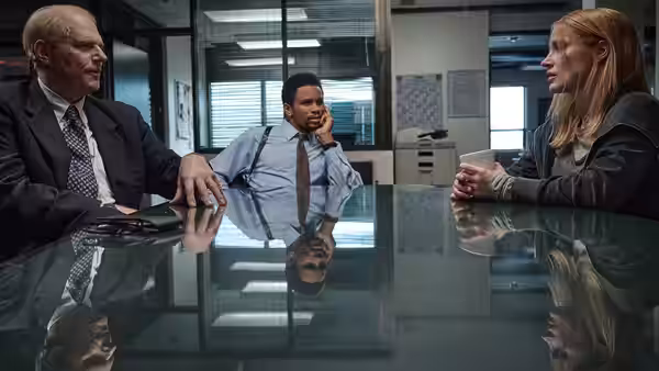 Amy Loughren (Jessica Chastain) speaks with two men across a glass conference table