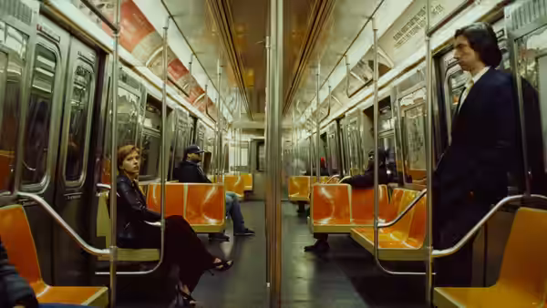 Nicole (Scarlett Johansson) seated in a subway car as Charlie (Adam Driver) stands nearby
