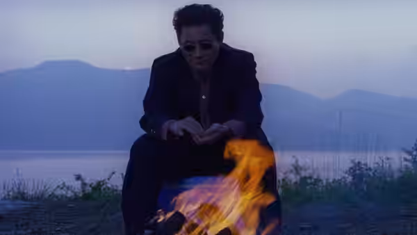 Yoshitaka Nishi (Takeshi Kitano) sitting by a fire at dusk