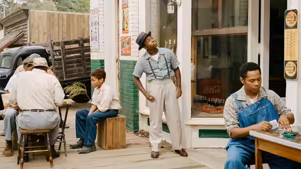 Emmett Till (Jalyn Hall) stands outside a storefront as men sit nearby