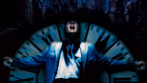 John Murdoch with arms outstretched and mouth open before a clock face