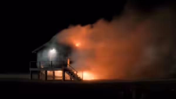 Wooden house burning at night on a dark open plain