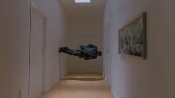 A man floats horizontally through a long empty hallway with doors