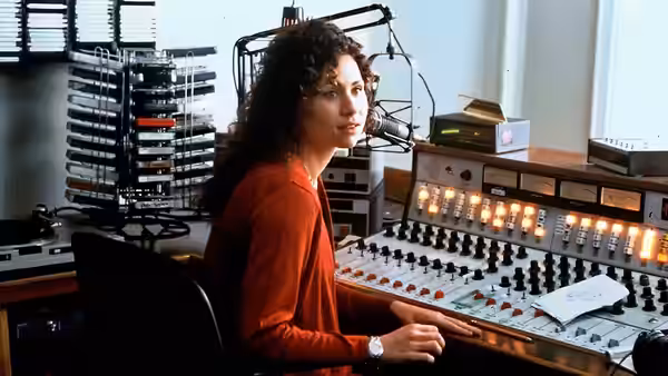 Debi Newberry (Minnie Driver) seated at a radio station mixing console