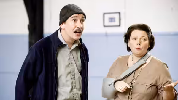 Man in beanie gesturing beside woman with arm sling looking surprised indoors