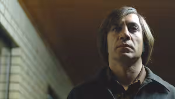Anton Chigurh (Javier Bardem) gazes upward in a close-up indoor portrait